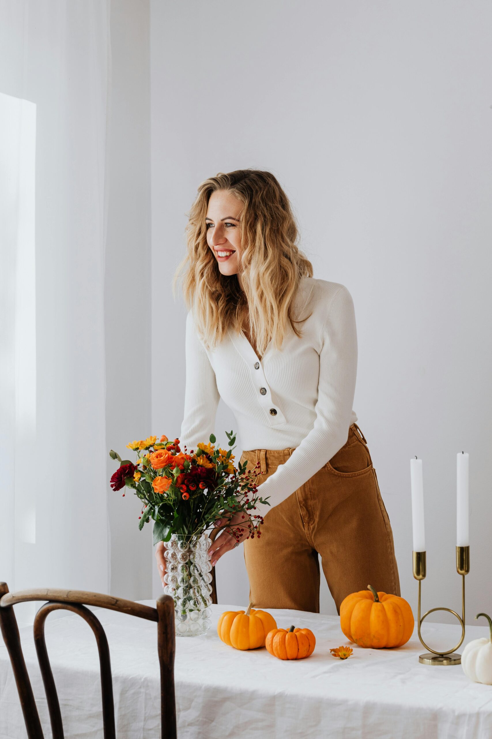 woman smiling and setting up dinner table with pumpkins after visiting dentist in Winter Haven